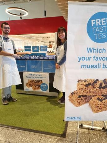 El personal de elección de pie frente a un banco de pruebas de sabor en un centro comercial